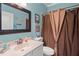 Well-lit bathroom features a black framed mirror, vanity with sink, and tiled shower with bronze fixtures and decorative curtain at 33925 Terragona Dr, Sorrento, FL 32776