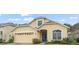 Charming yellow single Gathering home features a blue front door, arched windows, and a two car garage at 33925 Terragona Dr, Sorrento, FL 32776