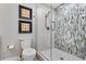 Modern bathroom featuring tiled shower with glass door, complemented by stylish seashell art at 6912 S Atlantic Ave, New Smyrna Beach, FL 32169