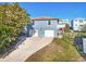 Blue two-story home featuring a two-car garage with a concrete driveway and mature landscaping at 6912 S Atlantic Ave, New Smyrna Beach, FL 32169