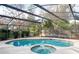 Inviting screened-in pool and spa with a wooden fence at 282 S Fox Chase Pt, Longwood, FL 32779