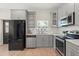 Another angle of the kitchen highlighting stainless steel appliances, subway tile, and gray cabinetry at 1875 Staunton Ave, Winter Park, FL 32789