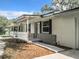 Side view of a renovated home showcasing a white exterior, covered porch and landscaping at 36810 Lake Unity Rd, Fruitland Park, FL 34731