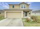 Two-story house with a beige exterior, two-car garage, and landscaping at 4269 Desert Rose Ave, Kissimmee, FL 34746