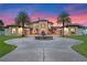 Elegant two-story home with fountain and palm trees at dusk at 5251 Carson St, St Cloud, FL 34771
