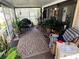 Comfortable screened porch with plants, seating, and a decorative rug, creating a relaxing outdoor space at 1960 Pinewood Ln, Mount Dora, FL 32757