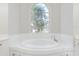 Relaxing bathroom with a large garden tub and an arched window at 2077 Wembley Pl, Oviedo, FL 32765