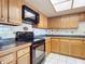 Kitchen with wood cabinets, black appliances, and tile countertops at 2810 Summerfield St, Deltona, FL 32738