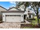 Two-story house with a beige exterior, a three-car garage, and a landscaped front yard at 1498 Moon Valley Dr, Davenport, FL 33896