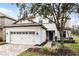 Two-story house with a beige exterior, a three-car garage, and a landscaped front yard at 1498 Moon Valley Dr, Davenport, FL 33896