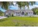 Charming single-story home with manicured lawn, white picket fence, and arched windows at 17901 Coralwood Ln, Groveland, FL 34736