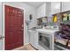 Laundry room with a red door, washer, dryer, and storage shelves at 17901 Coralwood Ln, Groveland, FL 34736
