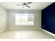 An empty bedroom with tiled floors, neutral colors, and a blue accent wall at 922 Umbria Dr, Poinciana, FL 34759