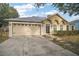 Tan house with a gray roof, two-car garage, and a concrete driveway at 1603 S Mary St, Eustis, FL 32726