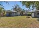 View of the home's backyard with a green lawn, gray shed, brick fire pit, and fresh landscaping at 2106 Cordova Dr, Sanford, FL 32771