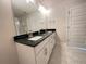 Double vanity bathroom with dark granite countertops and neutral tile floors at 3019 Tackle Drive, Leesburg, FL 34748