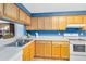 Kitchen with wood cabinets, blue walls, and white appliances at 513 Goodridge Ln, Fern Park, FL 32730