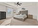 Spacious main bedroom with a tray ceiling, ceiling fan, and tufted headboard at 558 Pawnee Ct, Haines City, FL 33844