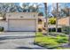 Tan stucco home with a two-car garage and lush landscaping at 706 Santa Cruz Ln, Howey In The Hills, FL 34737