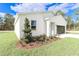 White house exterior showcasing landscaping and a black garage door at 7542 Sw 128 Terrace Rd, Dunnellon, FL 34432