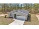 Charming single-story home with a grey exterior, white garage door, and well-maintained lawn at 7542 Sw 128 Terrace Rd, Dunnellon, FL 34432