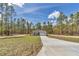Wide angle showing gray single story home with long driveway set amongst mature trees at 7542 Sw 128 Terrace Rd, Dunnellon, FL 34432