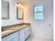 Bathroom vanity with granite counters, double sinks, two mirrors, and updated lighting at 13111 Point O Wood Ct, Orlando, FL 32828