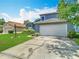 Well-maintained home with a large two-car garage, green lawn, and lush landscaping at 13111 Point O Wood Ct, Orlando, FL 32828