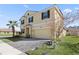 Two-story house, tan exterior, brown accents, paved driveway, and landscaping at 1504 Oak Marsh Loop, Davenport, FL 33837