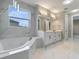 Luxurious bathroom with marble-like walls, soaking tub, and double sink vanity with modern fixtures at 1700 Underwood Ave, St Cloud, FL 34771