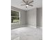 A serene bedroom with marble floors, a large window, and a ceiling fan at 1700 Underwood Ave, St Cloud, FL 34771
