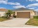 Tan house with gray roof, palm tree, and a two-car garage at 213 Lake Lucerne Way, Winter Haven, FL 33881