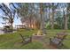 Scenic backyard featuring a stone fire pit and Adirondack chairs in a grassy area with lake and mature trees at 2250 W County Road 44, Eustis, FL 32726