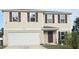 Two-story house with beige siding, brown shutters, and a two-car garage at 233 Gladiola Ct, Poinciana, FL 34759