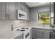 Modern kitchen featuring gray cabinets, white appliances, and quartz countertops at 2501 Center Ave, Orlando, FL 32806