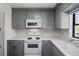 Updated kitchen with gray cabinets, white appliances, and quartz countertops at 2501 Center Ave, Orlando, FL 32806