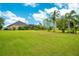 Large grassy backyard with tropical landscaping and home view at 2682 Wyndsor Oaks Pl, Winter Haven, FL 33884