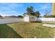 View of a large backyard with a detached garage behind a full, white privacy fence under a cloudy blue sky at 40 Lantana Dr, Debary, FL 32713