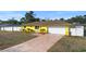 The house showcases a bright yellow facade, a neatly kept yard, and a brick-paved driveway, with a garage at 40 Lantana Dr, Debary, FL 32713