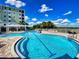 Enjoy the community pool with plenty of lounge chairs and scenic views under a bright blue sky with puffy white clouds at 5 Riverwalk Dr # 301, New Smyrna Beach, FL 32169