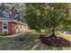 Side view of brick house with garden beds and large tree at 646 Palm Dr, Oviedo, FL 32765