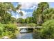 Serene landscaping with a bridge over a pond, lush greenery, and mature trees at 700 Melrose Ave # A 22, Winter Park, FL 32789