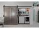 Laundry room with barn door, washer, dryer, and ample shelving at 1004 Hornbeam St, Oviedo, FL 32765