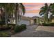 Charming single-story home with a brick driveway, lush landscaping, and a tile roof at sunset at 12161 Obelia Ln, Orlando, FL 32827