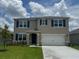 Two-story home with a front lawn and an attached two-car garage on a lot with a cloudy blue sky background at 2212 Lake Preserve Cir, New Smyrna Beach, FL 32168
