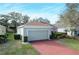 Front view of a light green house with a red brick driveway and lush landscaping at 2311 Caledonian St, Clermont, FL 34711