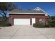 Exterior view of a two-car garage with brick siding and trimmed green bushes at 34122 Park Ln, Leesburg, FL 34788