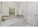 Relaxing bathroom with soaking tub and neutral tile at 34405 Alameda Dr, Sorrento, FL 32776