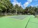 Green tennis court with white lines, surrounded by trees and a fence at 111 Millholland St, Oakland, FL 34760