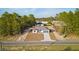 Aerial view of a charming one-story home surrounded by lush greenery and a long, paved driveway at 709 Marion Oaks Mnr, Ocala, FL 34473